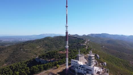 Drone-Shot-of-a-Radio-Station-on-top-of-an-Arid-Hill-under-a-Midday-Sun