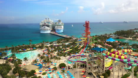 Breite-Rotierende-Drohnenaufnahme-Von-Cococay-Island-Mit-Wasserrutschen-Und-Einem-Königlichen-Karibischen-Kreuzfahrtschiff-Im-Hintergrund