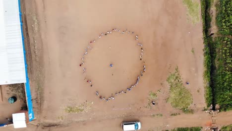 African-School-Children-Playing-Game-in-Yard-with-Teacher,-Drone-view