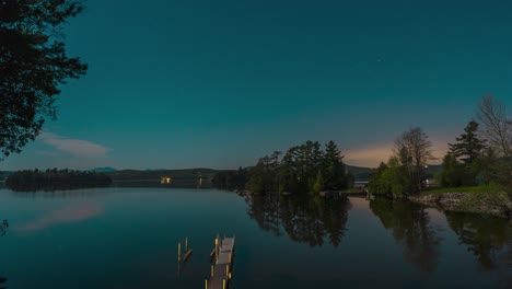 Star-filled-sky-over-rural-lake-time-lapse-with-full-moon-and-glowing-sunset