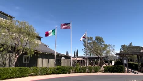 La-Bandera-De-Los-Estados-Unidos-Y-La-Bandera-Del-Estado-De-California-Ondeando-En-El-Viento-Contra-Un-Cielo-Azul-En-La-Bodega-Ponte