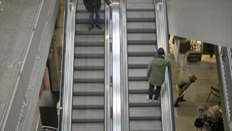 Un-Hombre-Con-Una-Chaqueta-Verde-Sube-Una-Escalera-Mecánica