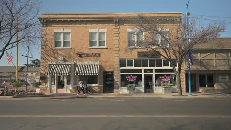 People-walk-on-sidewalk-past-shops-in-Kingsburg,-California