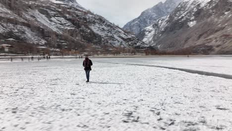 Adult-Male-Walking-Across-Frozen-Khalti-Lake-Wrapped-Up-Warm-With-Beanie-Hat-And-Scarf