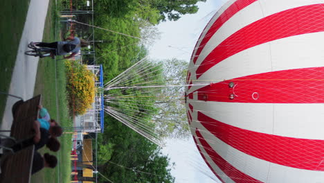 Vertical-video-of-people-relaxing-near-Balloon-Lookout-attraction,-City-Park,-Budapest