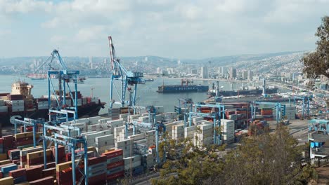 Valparaiso-seehafencontainer-Und--kräne,-Frachtschiffe,-Die-Darauf-Warten,-Beladen-Zu-Werden,-Hügelstadt-Im-Hintergrund,-Chile