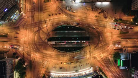 Aerial-top-down-hyperlapse-of-Grunwald-square-at-dusk-with-road-traffic-and-illuminated-public-transport-hub