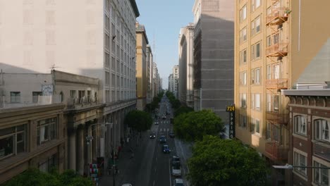 Summer-in-the-City,-Drone-Shot-Flying-Through-Downtown-Street,-Old-Buildings-and-Tree-Lined-Roads