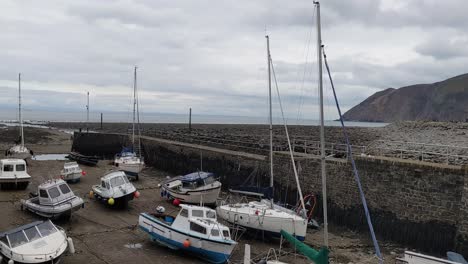 4k-Langsame-Schwenkaufnahme-Von-Booten-Im-Hafen-Von-Lynmouth-Und-Touristen-Mit-Dramatischen-Küstenklippen-Im-Norden-Von-Devon,-Großbritannien