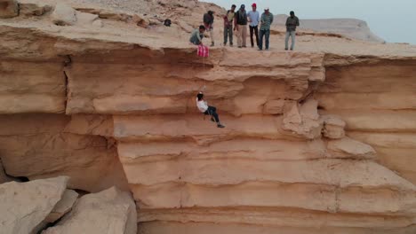 Drone-capture-the-aerial-view-of-man-climbing-down-the-ledge-of-a-mountain-in-Khairpur-Sindh-in-Pakistan