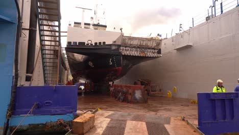 Walking-inside-drydock-with-ferryboat-inside-for-cleaning-of-ships-hull---Ferry-Hjellestad-from-Norled-company-inside-drydock-at-Westcon-yards-in-Olensvag-Norway
