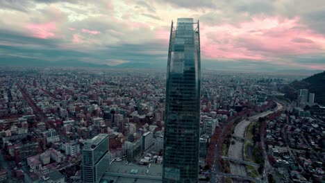 Aerial-orbit-of-Providencia,-Costanera-Tower-with-a-cloudy-background-after-the-rain,-Santiago,-Chile
