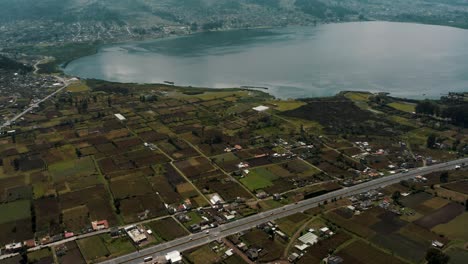 Fruchtbares-Und-Grünes-Wohndorf-Am-Seeufer-Der-Lagune-Von-San-Pablo-Mit-Dichten-Wolken,-Die-Die-Spitzen-Des-Vulkans-Imbabura-In-Otavalo,-Ecuador-Bedecken