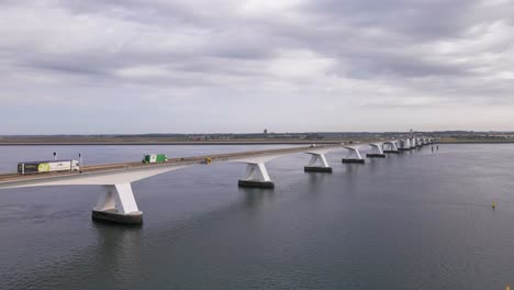 Mehrere-Lastwagen-Und-Andere-Fahrzeuge-Fahren-An-Einem-Bewölkten-Morgen-über-Die-7-Km-Lange-Zeeland-brücke-Im-Südwesten-Der-Niederlande