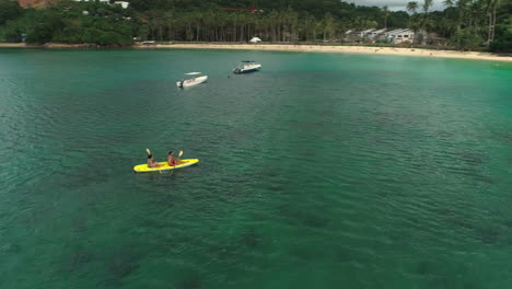 Órbita-Aérea-De-Una-Pareja-Joven-En-Kayak-En-El-Nido,-Filipinas