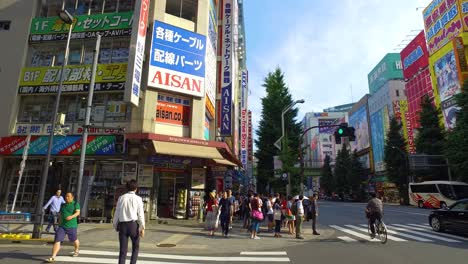 POV-walking,-Crowds-pass-below-colorful-signs-in-Akihabara