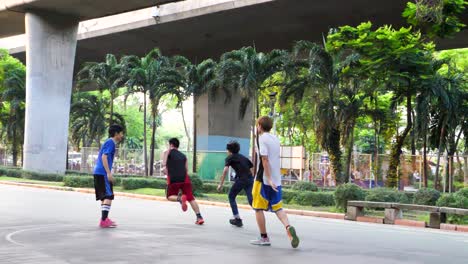 Niños-Jugando-Baloncesto-Bajo-La-Autopista-En-El-Distrito-De-Saphan-Taksin-De-Bangkok,-Tailandia