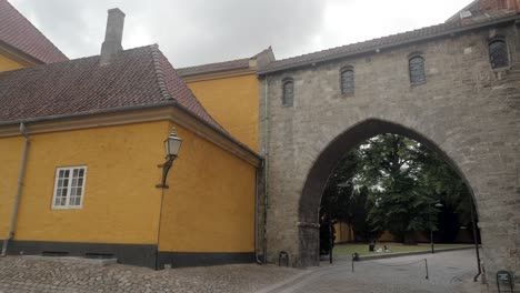 Man-biking-through-The-Absalon-Arch-between-Roskilde-Cathedral-and-the-Museum-of-Contemporary-Art-in-Roskilde,-Denmark