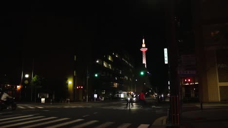Kyoto-Tower-Mit-Lichtern-Bei-Nacht-Und-Vorbeifahrendem-Verkehr-Davor