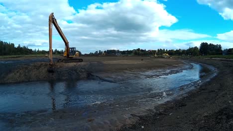 Yellow-Excavator-Works-with-Bucket-to-Clear-Mud-Sludge-and-Debris-from-the-Bottom-of-the-Drained-River