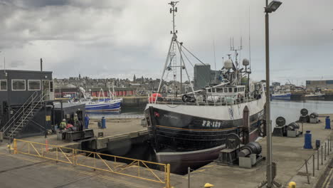 Ein-Zeitraffer-Eines-Fischereischiffs,-Das-Auf-Einem-Shiplfit-In-Das-Trockendock-Des-Hafens-Von-Fraserburgh-Gehoben-Wird,-Um-Reparaturarbeiten-Durchzuführen,-Mischung-Aus-Sonne-Und-Regen,-Fraserburgh,-Aberdeenshire