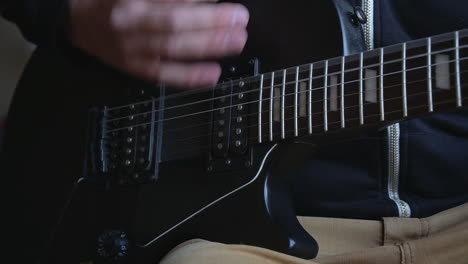 Man-Practising-a-vintage-black-electric-guitar,-rehearsing-chords,-solos-and-octaves-in-a-natural-light-environment.