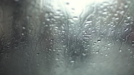 Regentropfen-In-Zeitlupe,-Die-Ein-Autofenster-Mit-Bokeh-Effekt-Im-Hintergrund-Herunterfallen