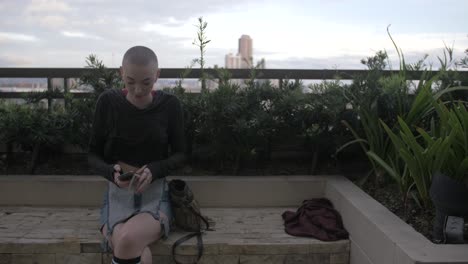 A-pretty-woman-with-short-hair-enjoying-a-rooftop-garden-takes-her-phone-from-her-purse-and-talks