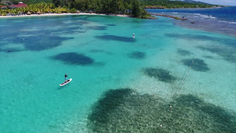 Slow-motion-aereal-view-of-people-paddleboarding-near-a-resort’s-beach-on-the-Honduran-caribbean-sea