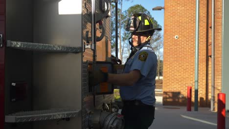Feuerwehrmann-Arbeitet-Am-Frühen-Morgen-An-Ausrüstung-Und-Feuerwehrschläuchen-An-Einem-Feuerwehrauto,-Um-Sich-Auf-Notfallmaßnahmen-Vorzubereiten