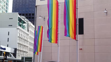 Slow-motion-flags-waving-in-the-wind,-tilt-up-revealing-city-skyline