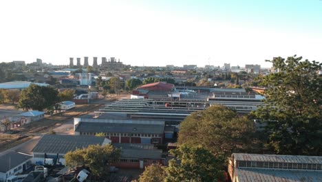 A-push-forward-drone-shot-of-Industry-buildings-in-the-outskirts-of-Bulawayo,-Zimbabwe-at-sunset