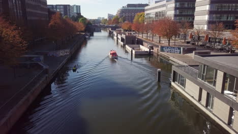 Motorboat-is-slowly-cruising-down-the-channel-on-a-sunny-afternoon-and-passing-by-a-houseboat-estate