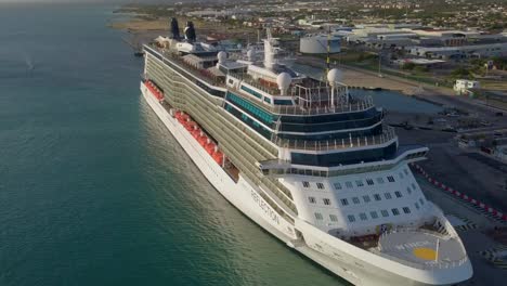 Aerial-view-with-panning-movement-of-a-big-cruise-ship-in-dock-with-the-sun-shining-on-it