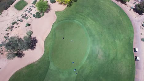 Ascenso-Aéreo-Lento-Sobre-Un-Green-Donde-Un-Grupo-De-Golfistas-Observan-Cómo-Uno-De-Ellos-Intenta-Y-Falla-Un-Putt-Largo,-Campo-De-Golf-Westin-Kierland,-Scottsdale,-Arizona