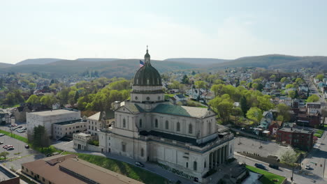 Aerial-drone-view-of-the-Cathedral-of-the-Blessed-Sacrament-in-Altoona,-Pennsylvania-with-the-American-flag-seen-behind