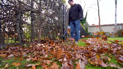 Unordentliche-Herbstblätter,-Die-An-Einem-Bewölkten-Tag-Von-Einem-Gärtner-Mit-Einem-Laubbläser-In-Zeitlupe-Geblasen-Wurden