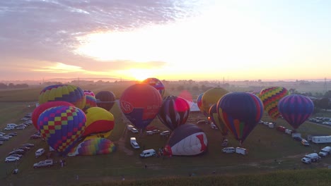 Luftaufnahme-Eines-Morgendlichen-Starts-Von-Heißluftballons-Bei-Einem-Ballonfestival-Vom-Befüllen-Bis-Zum-Abheben,-Wie-Von-Einer-Drohne-Gesehen