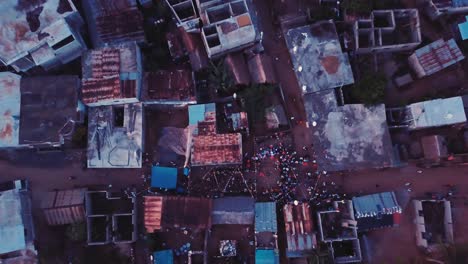 Aerial-zoom-out-drone-shot-of-People-and-families-at-a-wedding-party-in-the-streets-of-a-small-rural-town,-surrounded-by-empty-streets-of-the-village-in-the-Comoros,-Africa