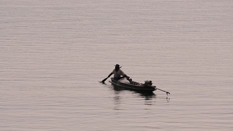 Fisherman-silhouetting-as-he-is-casting-and-drawing-his-net-in-the-River-before-dark,-in-slow-motion