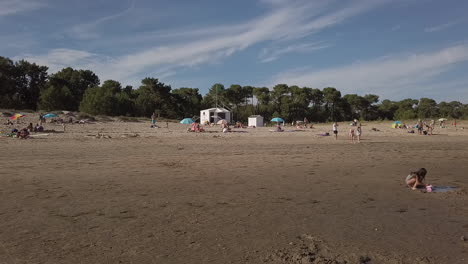 Holiday-families-with-children-settled-on-the-golden-sand-of-Gatseau-beach-at-low-tide,-Ile-d'Oléron