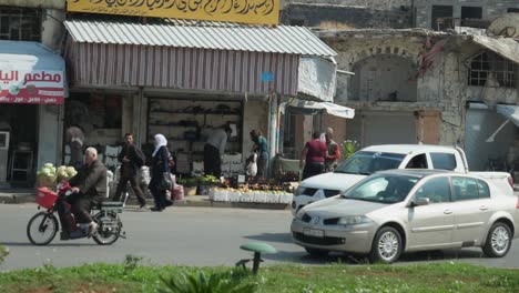 Cámara-Lenta,-Coches-Pasando-Y-Gente-Caminando-Por-La-Calle-De-La-Ciudad-De-Homs