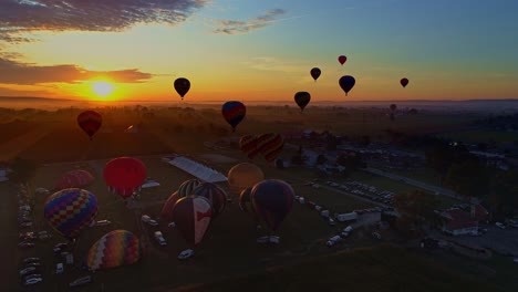 Luftaufnahme-Eines-Morgendlichen-Starts-Von-Heißluftballons-Bei-Einem-Ballonfestival-Vom-Befüllen-Bis-Zum-Abheben,-Wie-Von-Einer-Drohne-Gesehen