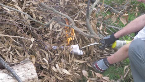 A-close-up-shot-of-a-man-starting-a-bonfire-with-a-gas-lighter