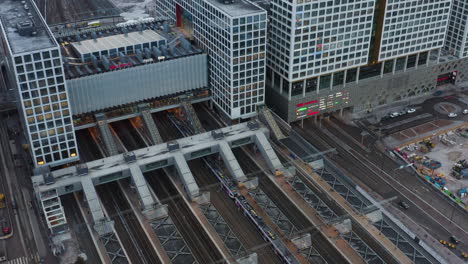 Aéreo,-Estático,-Tiro-De-Drones-De-Trenes-Y-Tráfico,-Frente-Al-Centro-Comercial-Del-Centro-Comercial-Tripla,-Y-La-Estación-De-Tren-Pasila,-En-Una-Tarde-Parcialmente-Soleada,-En-Helsinki,-Finlandia