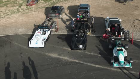 Racing-Cars-Parked-On-The-Road-Side-At-The-Hill-In-Imtahleb-Malta-For-Maintenance-Check-On-A-Sunny-Day---Aerial-Shot