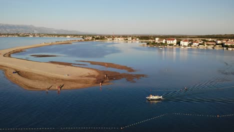 Luftpanorama-Einer-Nin-Stadt,-Eines-Sandstrandes,-Einer-Lagune-Und-Eines-Bootes,-Das-Sich-Im-Sonnenuntergang-Nähert