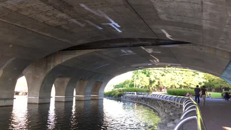 People-walk-under-a-bridge-at-Hosu-Park,-Janghang-dong,-Ilsan-gu,-Goyang-si,-Gyeonggi-do,-South-Korea