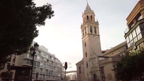 Cars-and-People-Pass-by-Gothic-Mudejar-Church-Tower-in-Seville,-Spain