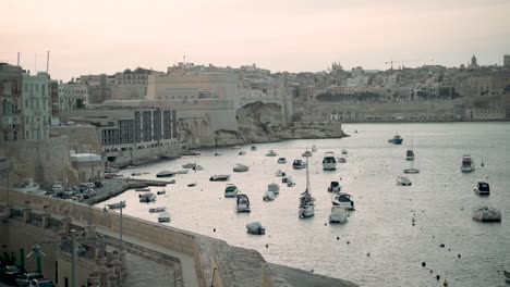 Boats-and-yachts-at-the-beautiful-harbour-of-Valletta,-Malta-at-dusk